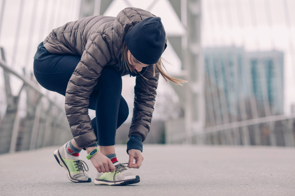 Woman crouching to tie her sneakers before a walk