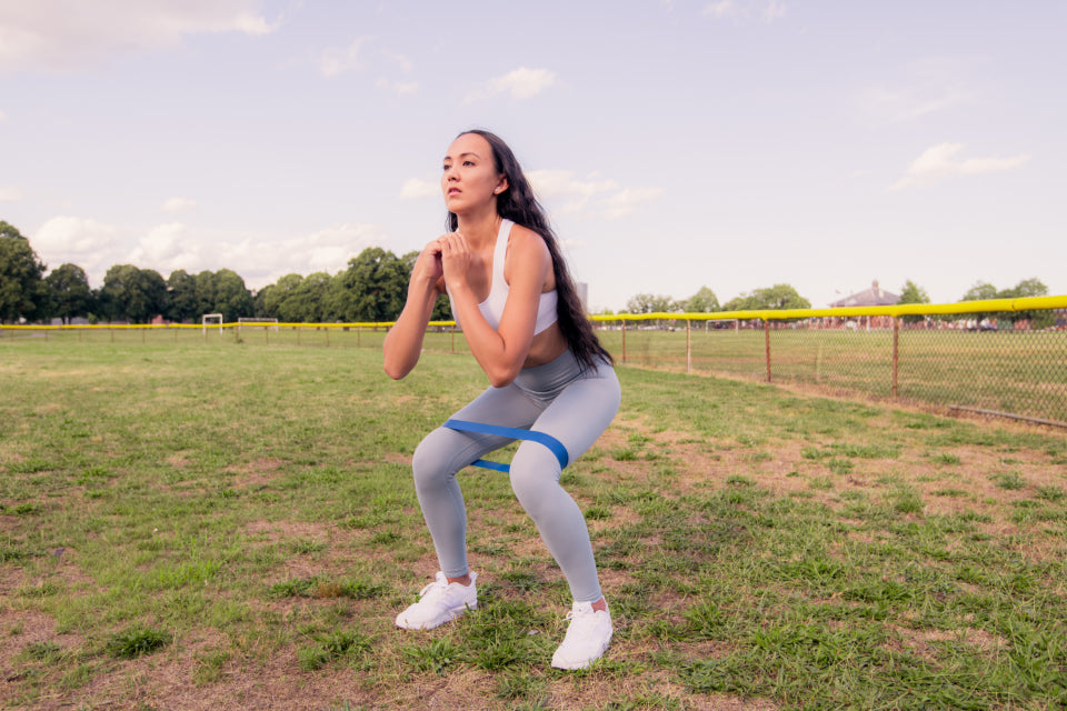 Woman doing a squat with a resistance band outdoors