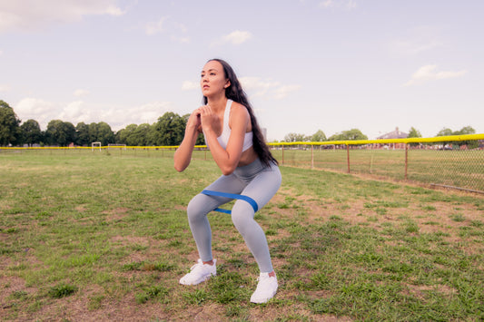 Woman doing a squat with a resistance band outdoors