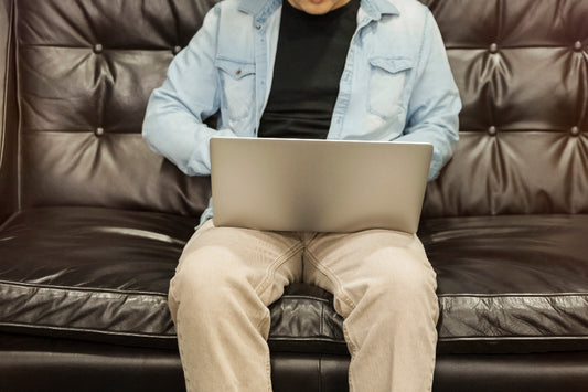 Man sitting on a leather couch with a laptop
