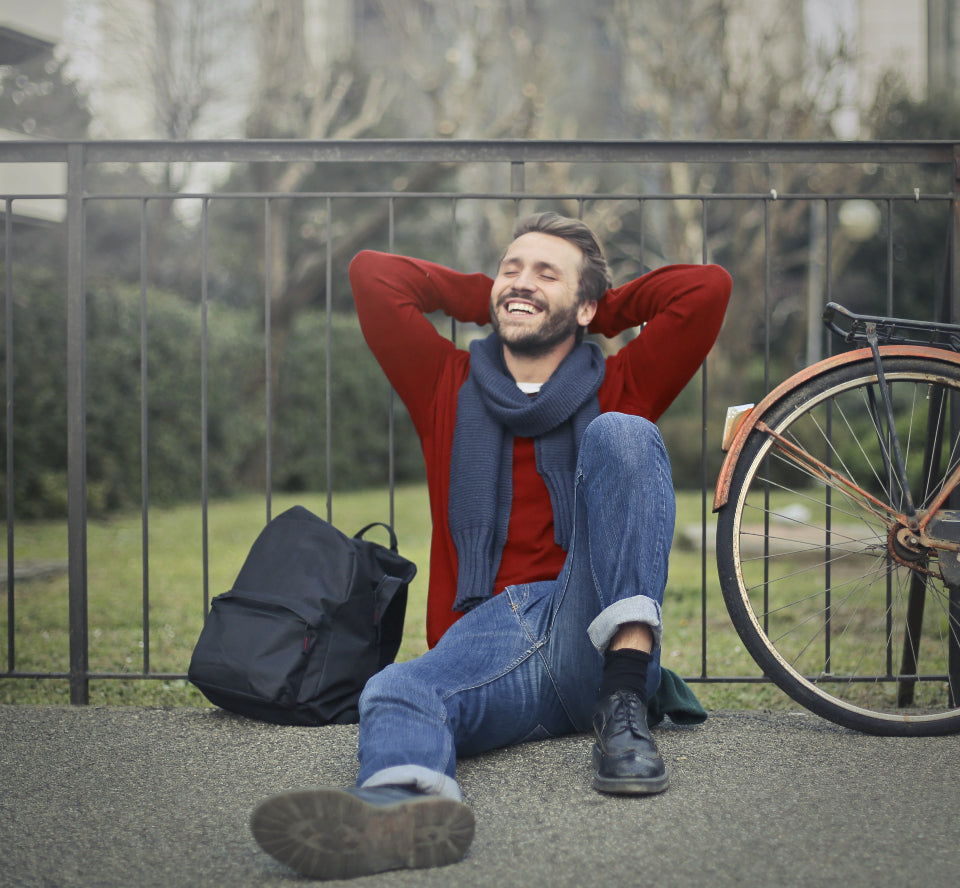 Smiling man sitting relaxed outdoors next to a bicycle