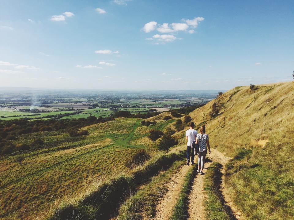 Two people walking along a grassy hill path