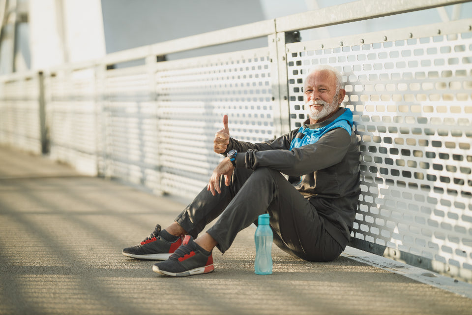 Older man in sportswear resting on a bridge after exercise