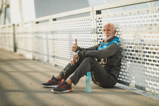 Older man in sportswear resting on a bridge after exercise