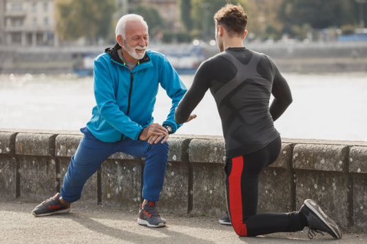 Older man doing a lunge exercise with a trainer outdoors