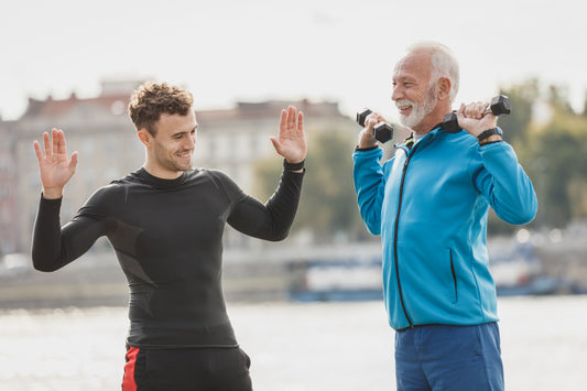 Older man exercising with light dumbbells next to a trainer