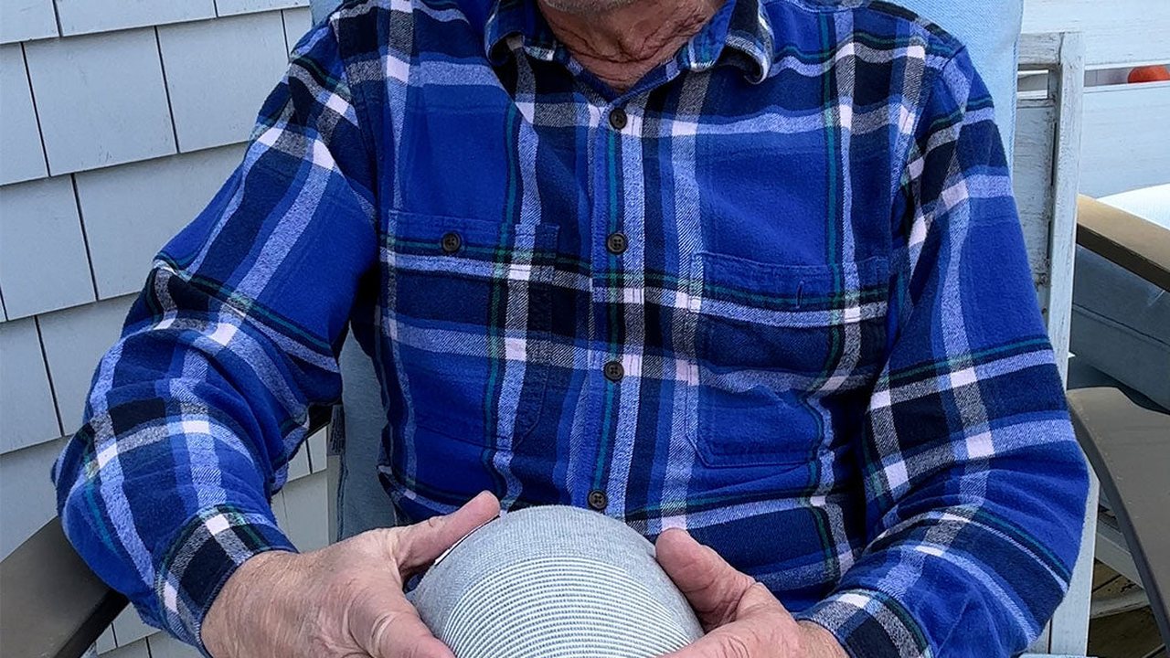 stariji muškarac sedi i drži steznik na kolenu